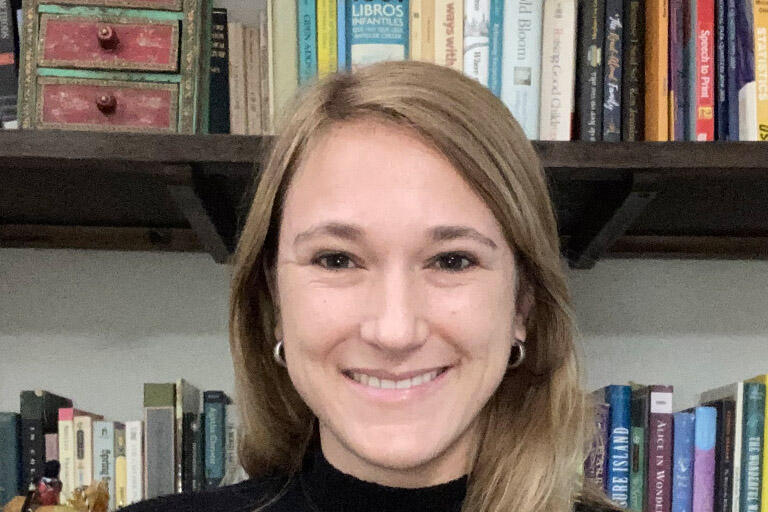 portrait image of doctoral candidate Monica Zegers Larrain wearing a black shirt standing in front of a bookshelf